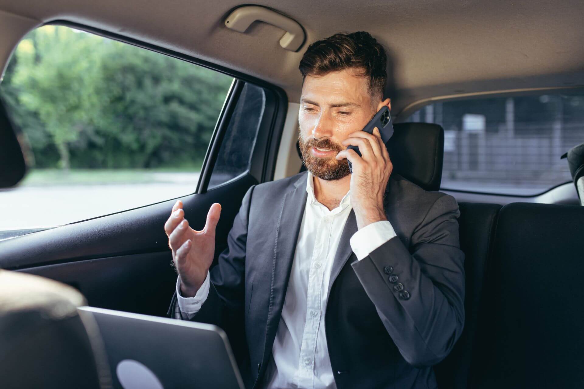 A Person in Business Attire Sitting in the Backseat of a Car, Seemingly Engaged in a Conversation With a Technical Support