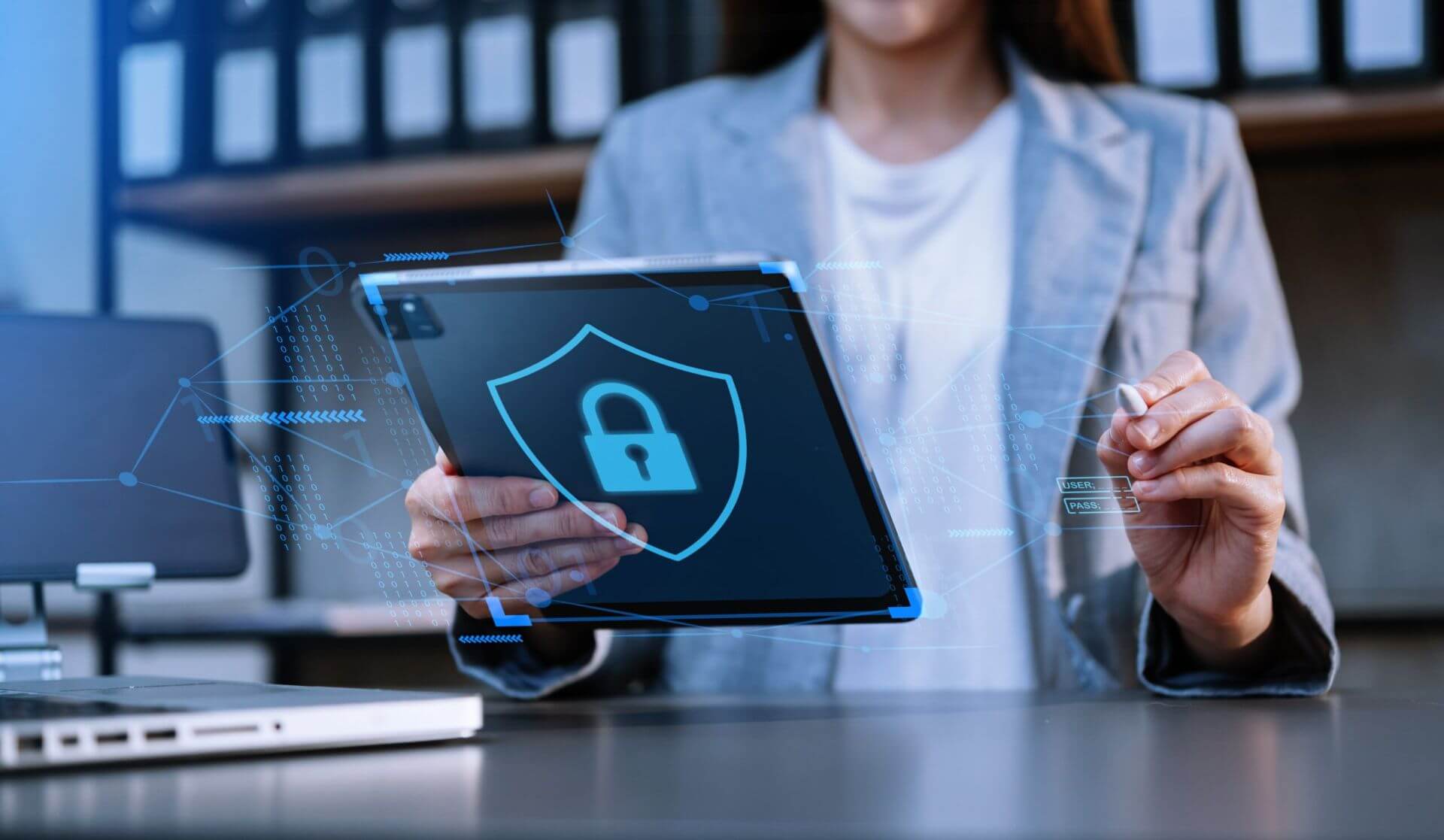 A Woman in a Blazer Holds a Tablet Working as a Cyber Security Analyst